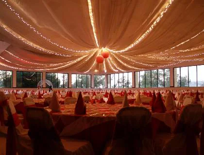 Salón con telas ámbar en el techo y series de luces sobre las mesas